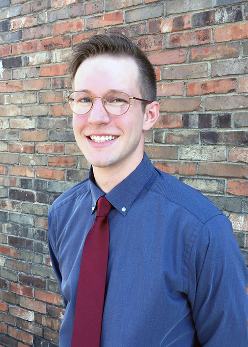 Rayce Belton headshot wearing blue shirt and red tie