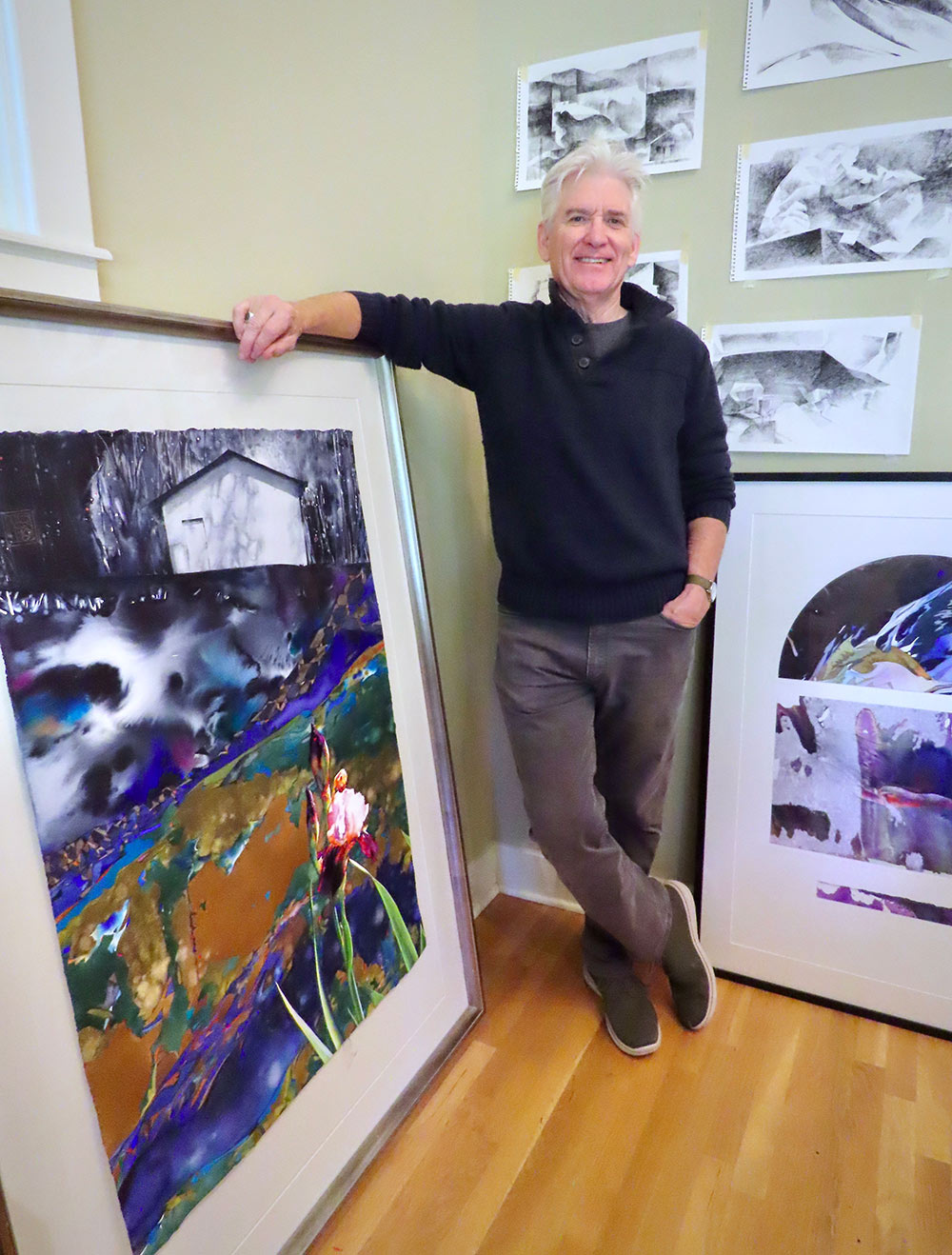 Brent Funderburk, right, leans on a large watercolor painting of a house and flower