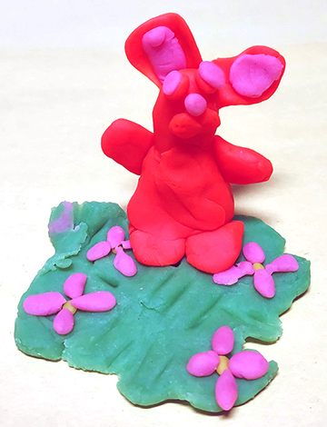 Clay sculpture of a rabbit and flowers.