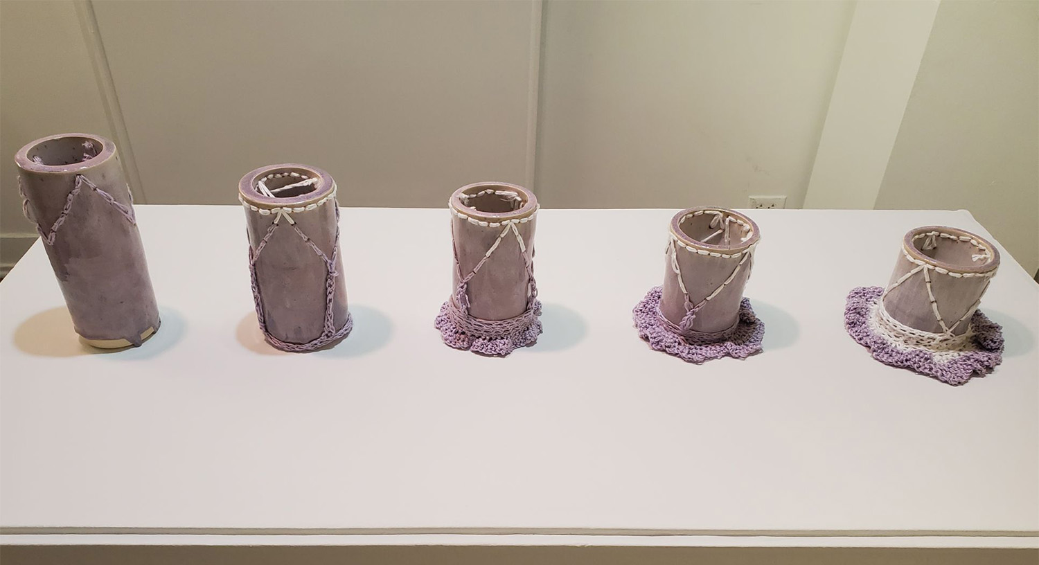 A set of purple cylinders with crochet pooling around them.