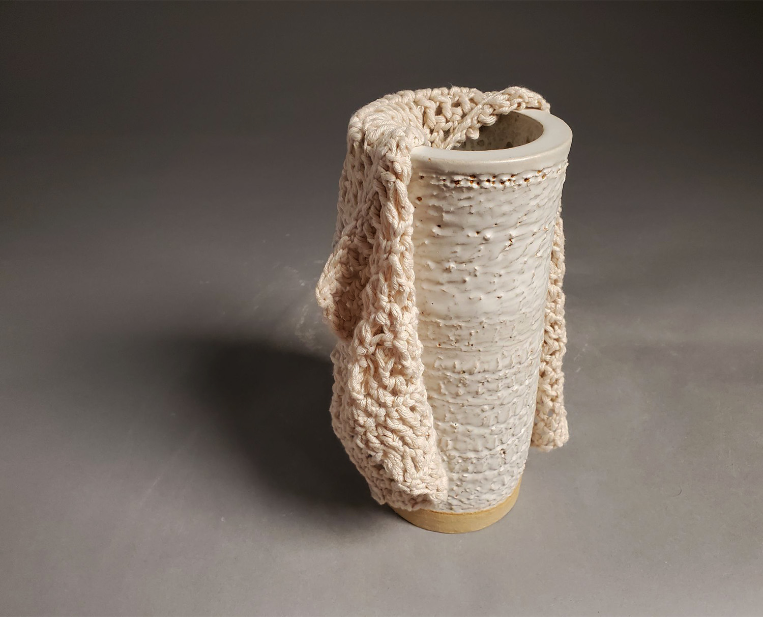 A white cloth half draped over a white pottery cylinder.