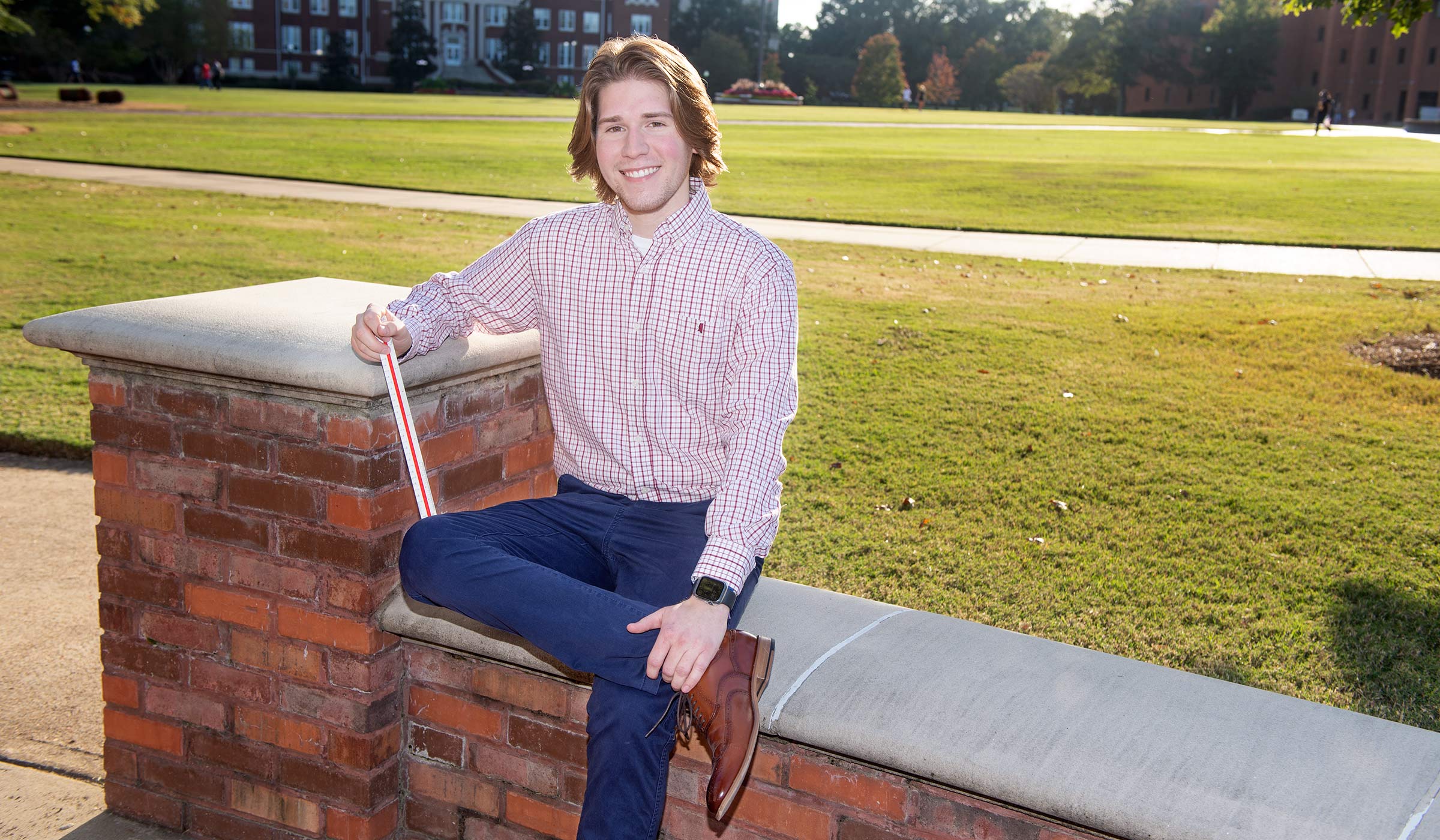 Cary Reynolds posed, sitting down on the Drill Field with his leg crossed over the other.