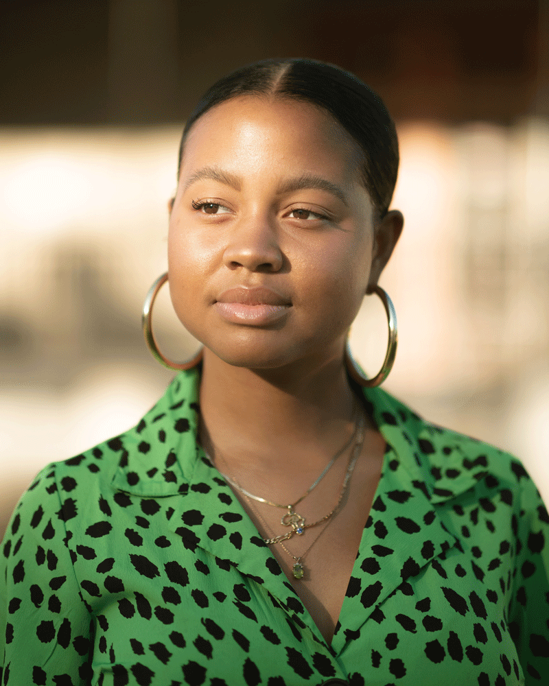 Christina McField looking off camera in a green and black blouse.