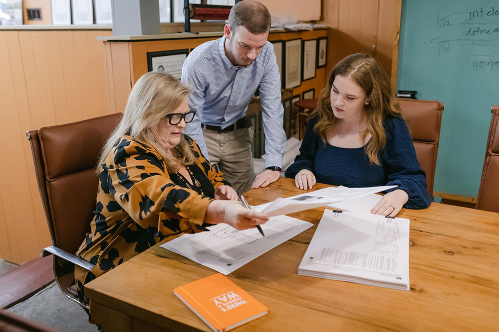 Belinda Stewart, left, sitting, works with employees at table with paper