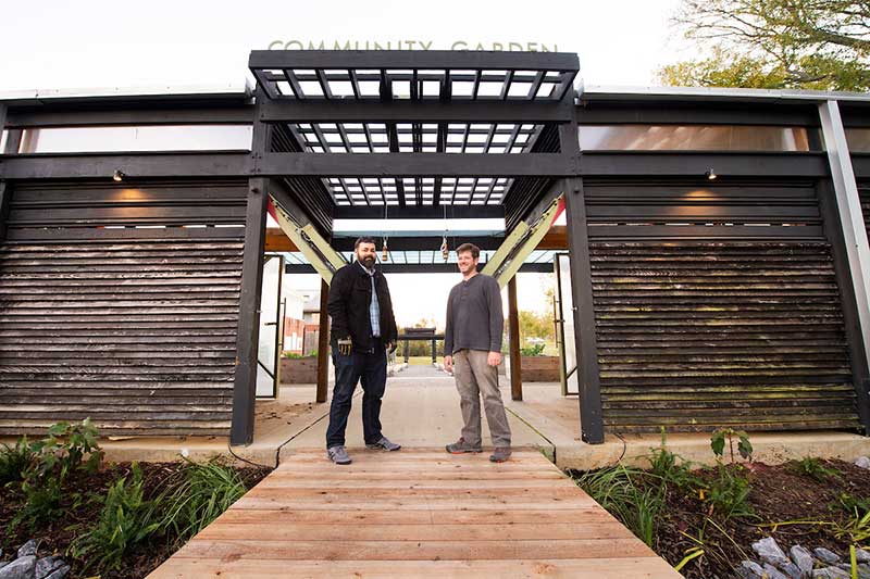 Hans Herrmann, left, stands under MSU Community Garden pergola with Cory Gallo, right