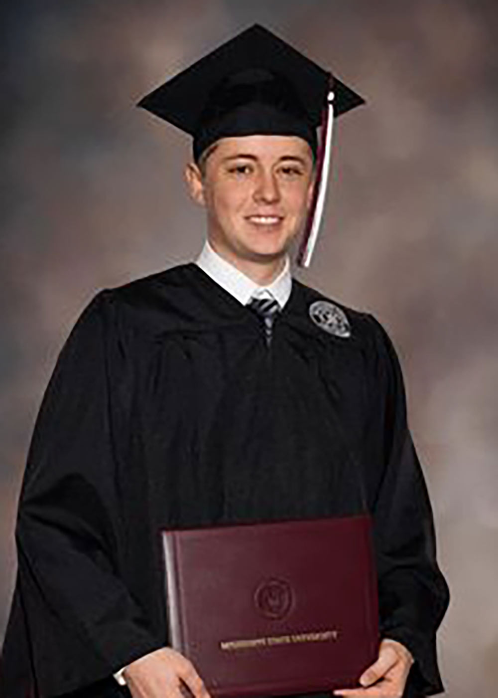 Donald Crotwell holds MSU diploma in graduation attire