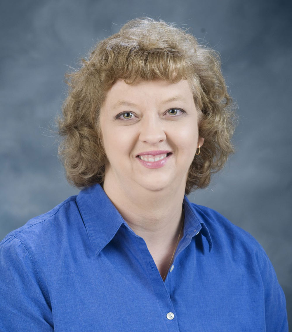 Amy Crumpton, smiling, and wearing a blue button-up blouse.