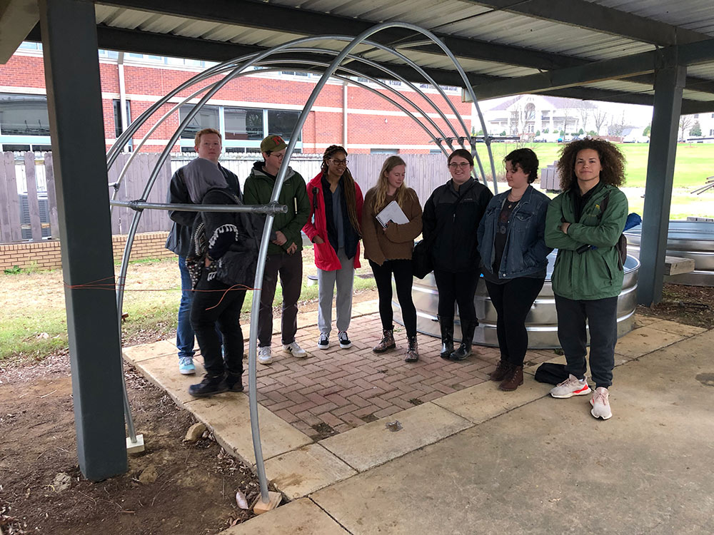 students pose under metal sculpture