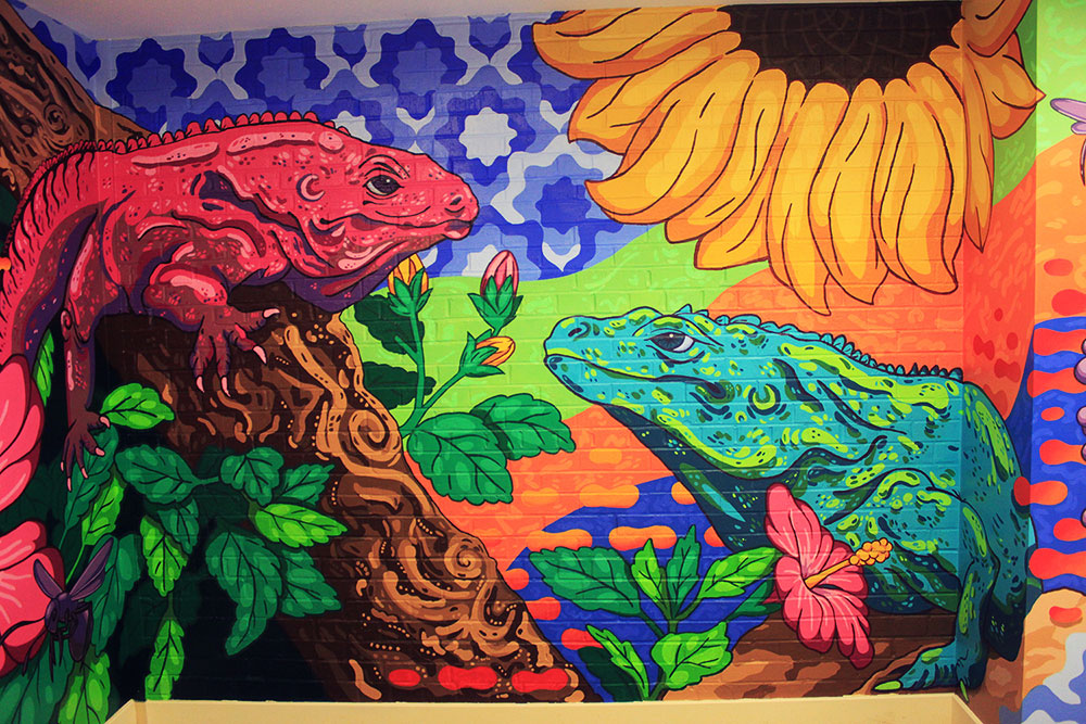 Colorful mural of two lizards, one pink, one blue. surrounded by several colorful flowers and other various bugs. 