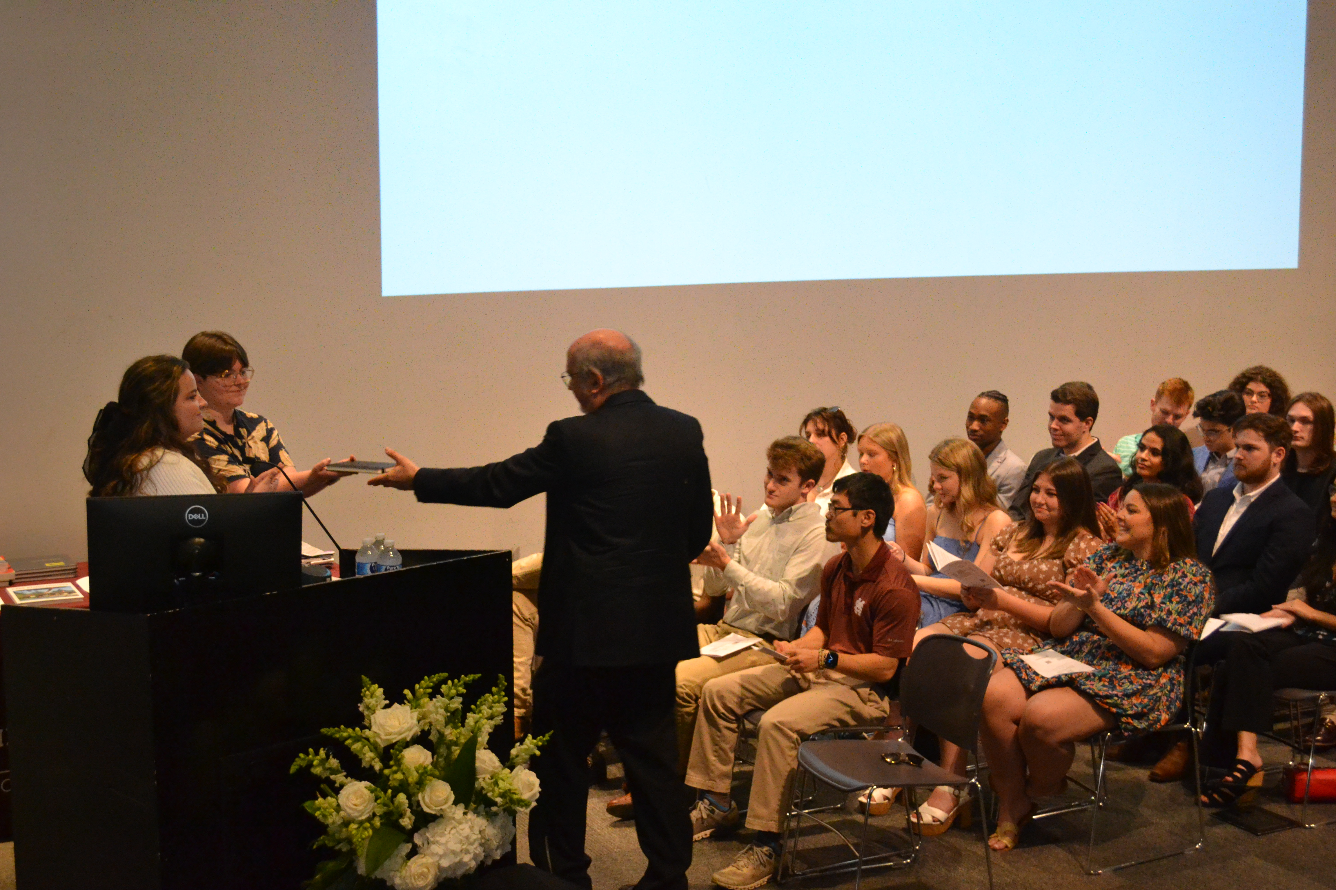 Caeli Finch, left, hands award to Professor John Poros