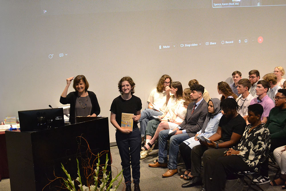 Jay Snodgrass holds book award on stage, posing for photo