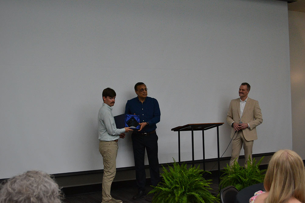 Read Robertson, left, accepts award from Dept. Head Syed Ahmed as Bo Oswalt, far right, watches