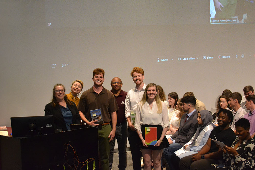 students pose with professors on stage