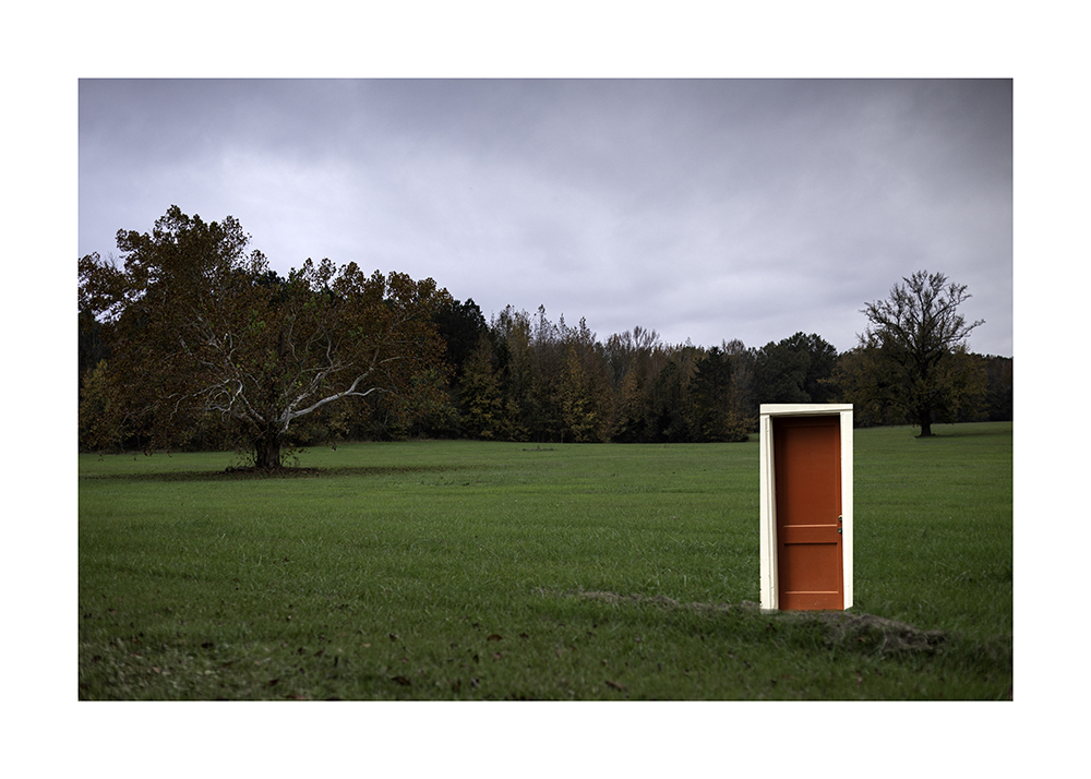 A bright red door is photoshopped into a field 