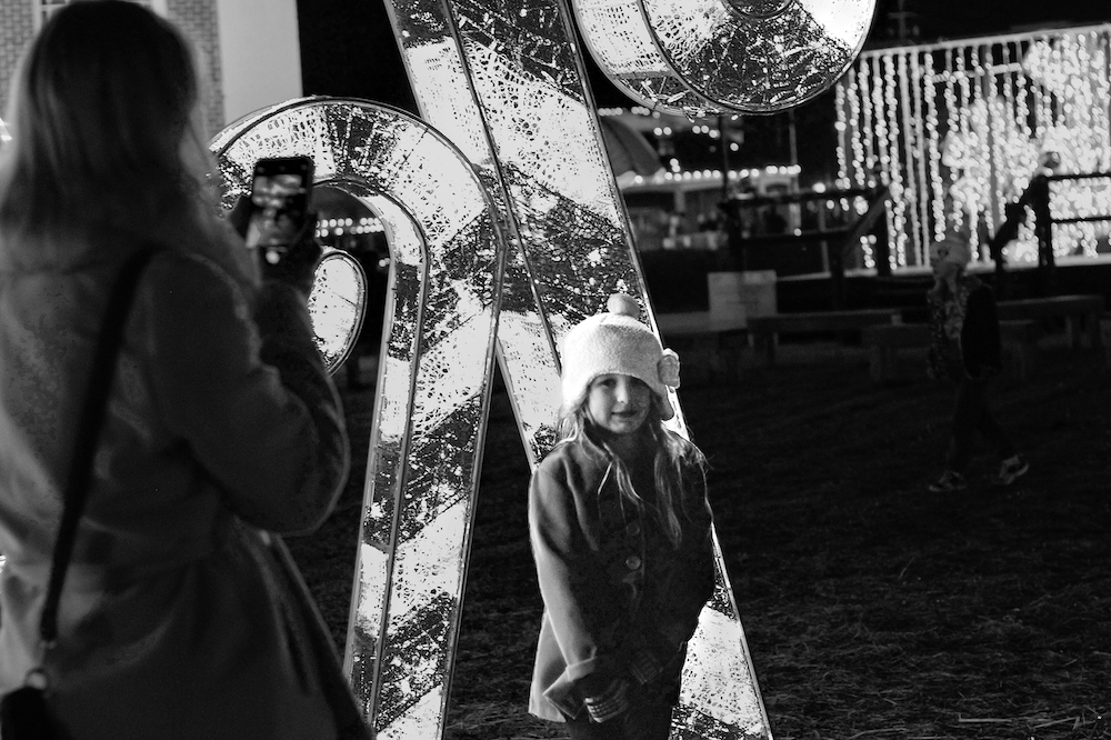 Photograph of a small child standing in front of a cand cane christmas decoration