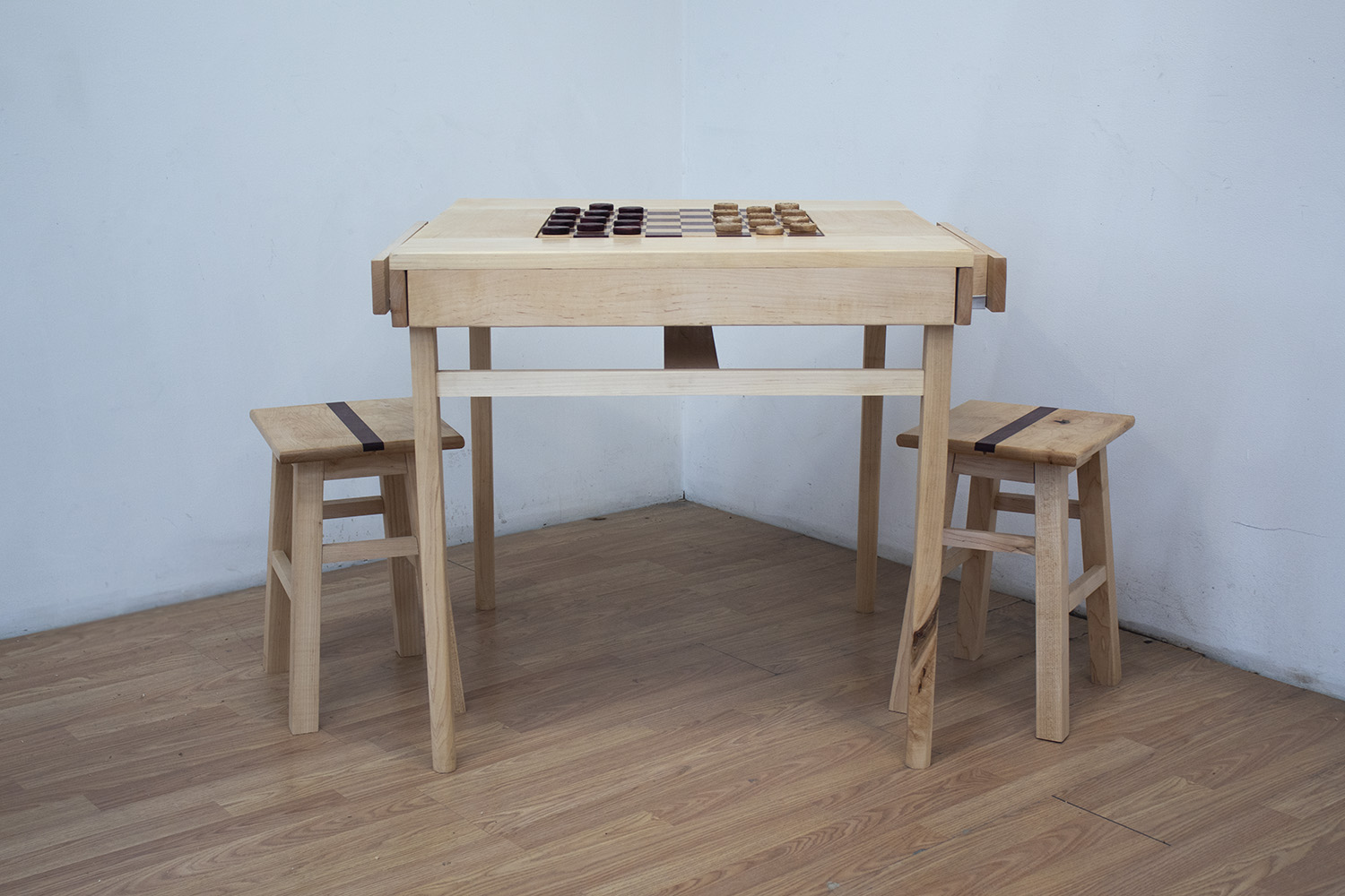 A simple table constructed with maple wood. The center contains an inlaid checkerboard constructed with maple and purple heart.