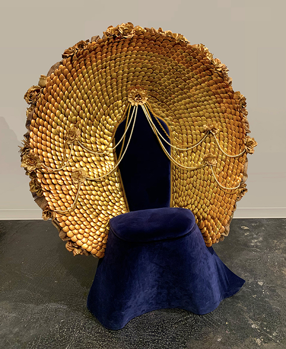 Blue velvet covered chair with golden back in shape of a large circle.