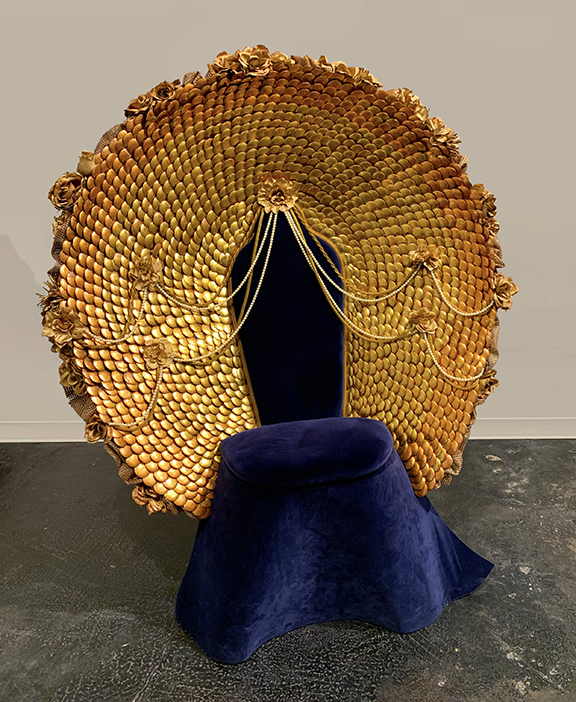 Blue velvet covered chair with golden back in shape of a large circle.