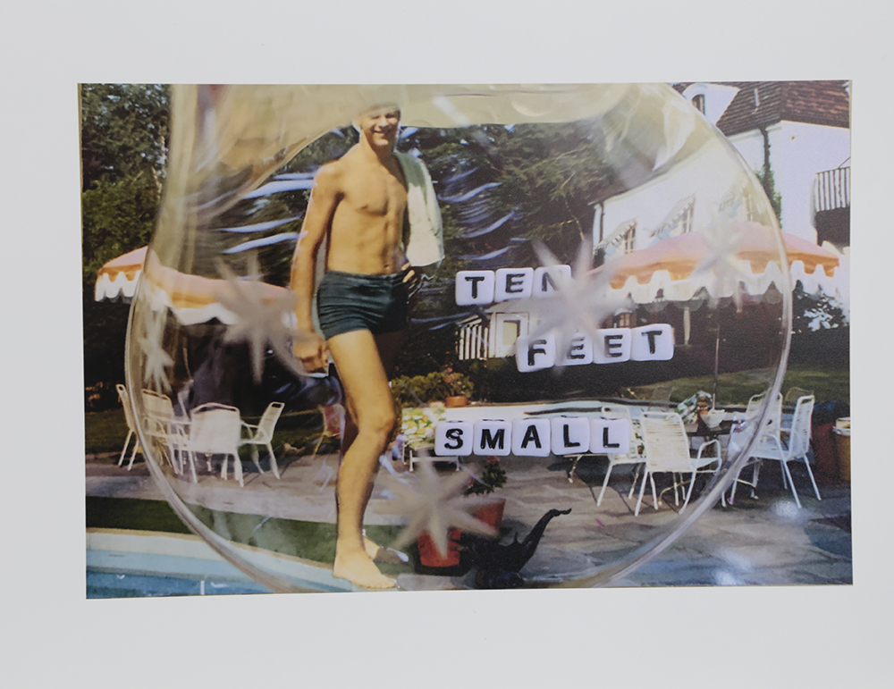 A photograph of a man inside of a bubble like figure that reads "ten feet small" in small box like letters