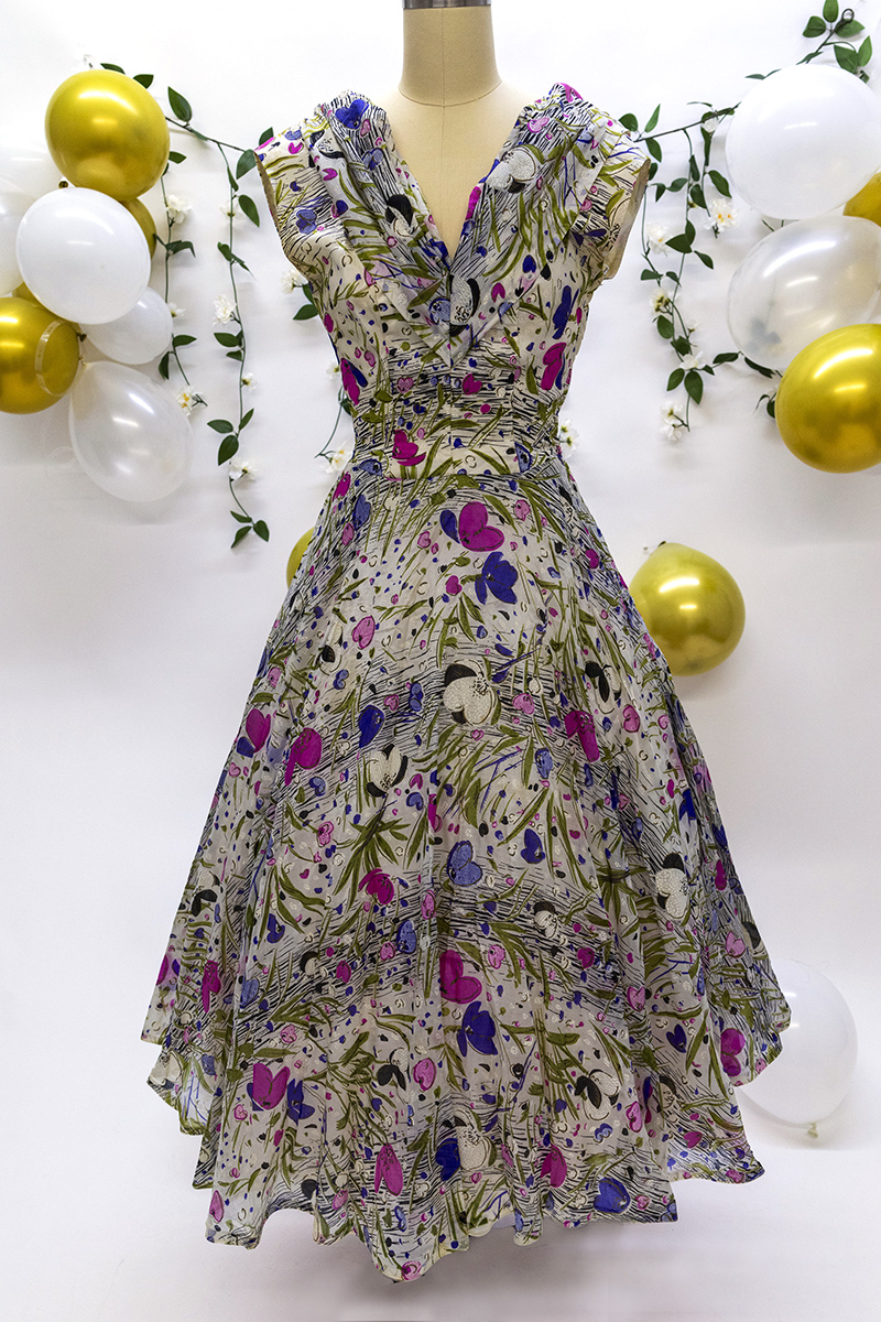 Sleeveless 1950s silk dress with floral print and full skirt.