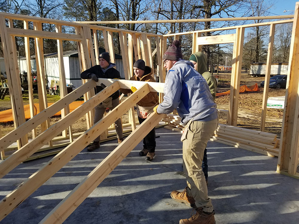 people work to lift wood wall frame