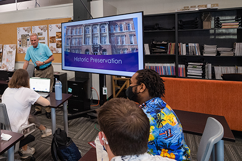 View from behind students listening to MSU Assistant Professor Glen Fulton next to TV screen that says "Historic Preservation" 