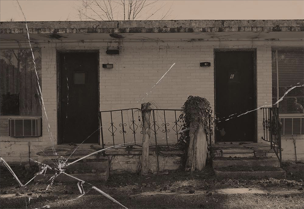 An image of a rundown home with what seems to be a piece of cracked glass on the image. 