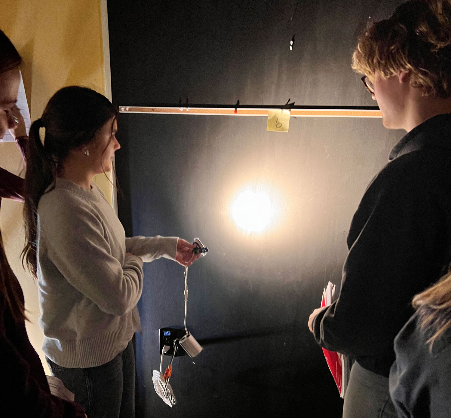 students shine light on wall in lighting lab