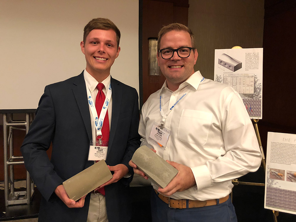 Team member Baron Necaise (left) and Assistant Professor of Architecture Jacob A. Gines hold concrete-cast prototypes of “The Pulse” brick at the National Concrete Masonry Association (NCMA) 2018 Midyear Meeting in Chicago following Necaise’s first-place project presentation.
