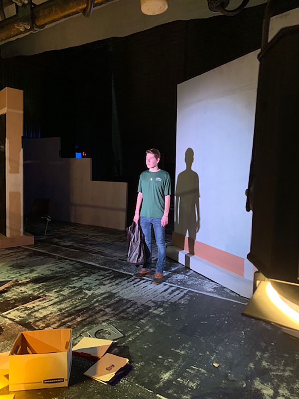 student stands in front of projector screen in the theatre