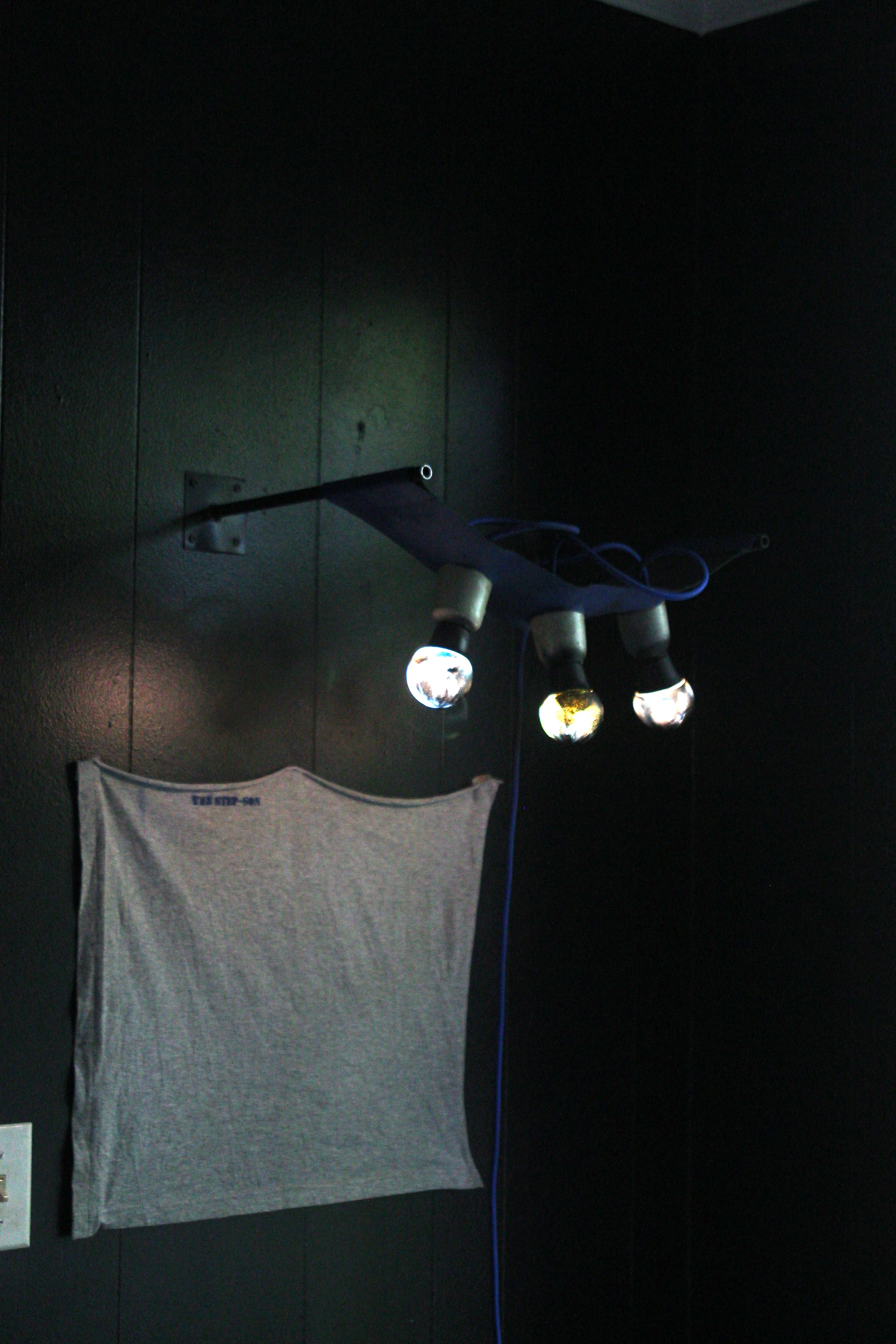 light ficture mounted into wall with 3 lights and ceramic housing in leather sling on metal framing. dim lighting