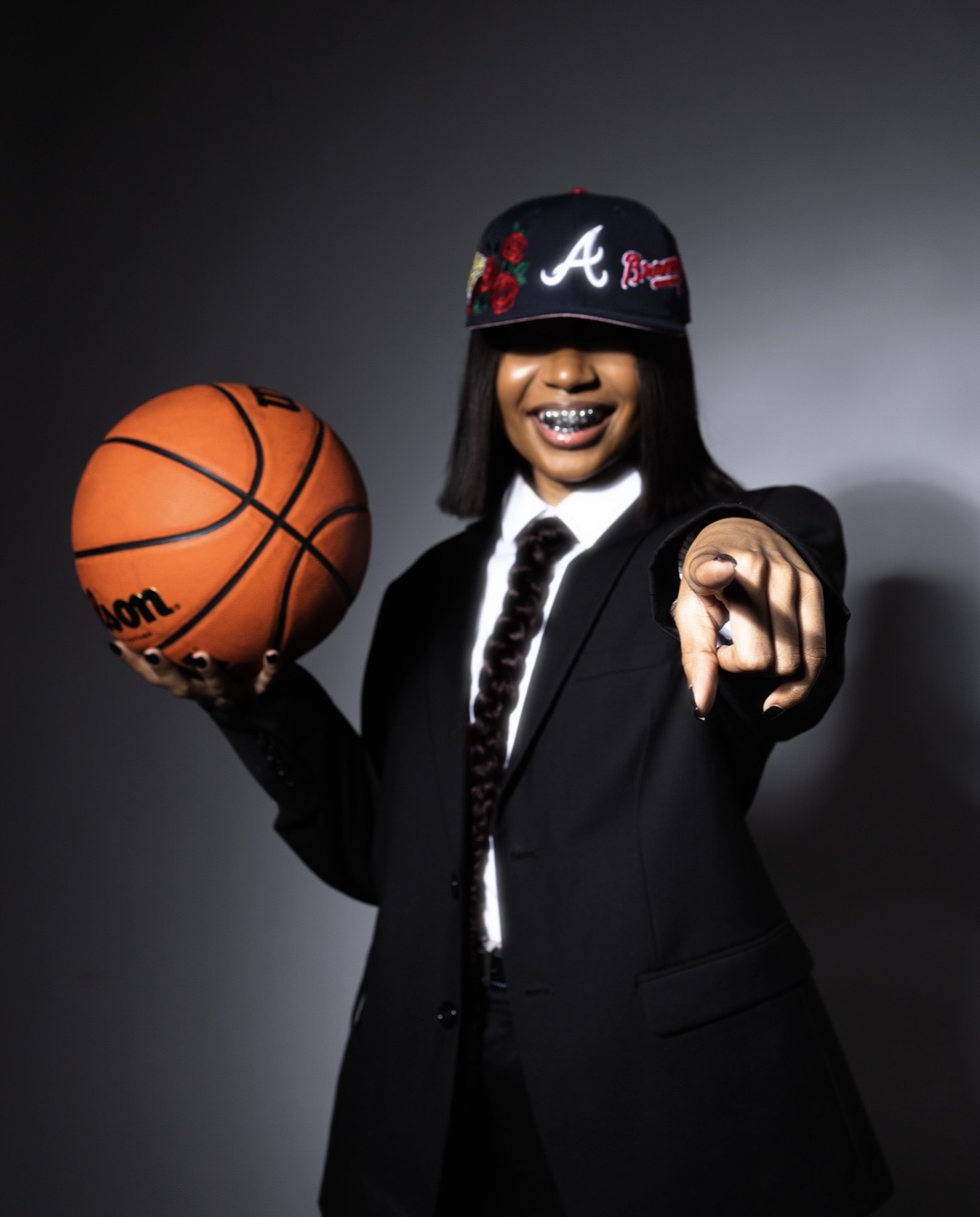 Photo by Jahari Bell from his "A Man's World" series shows a woman in a black suit pointing and holding a basketball
