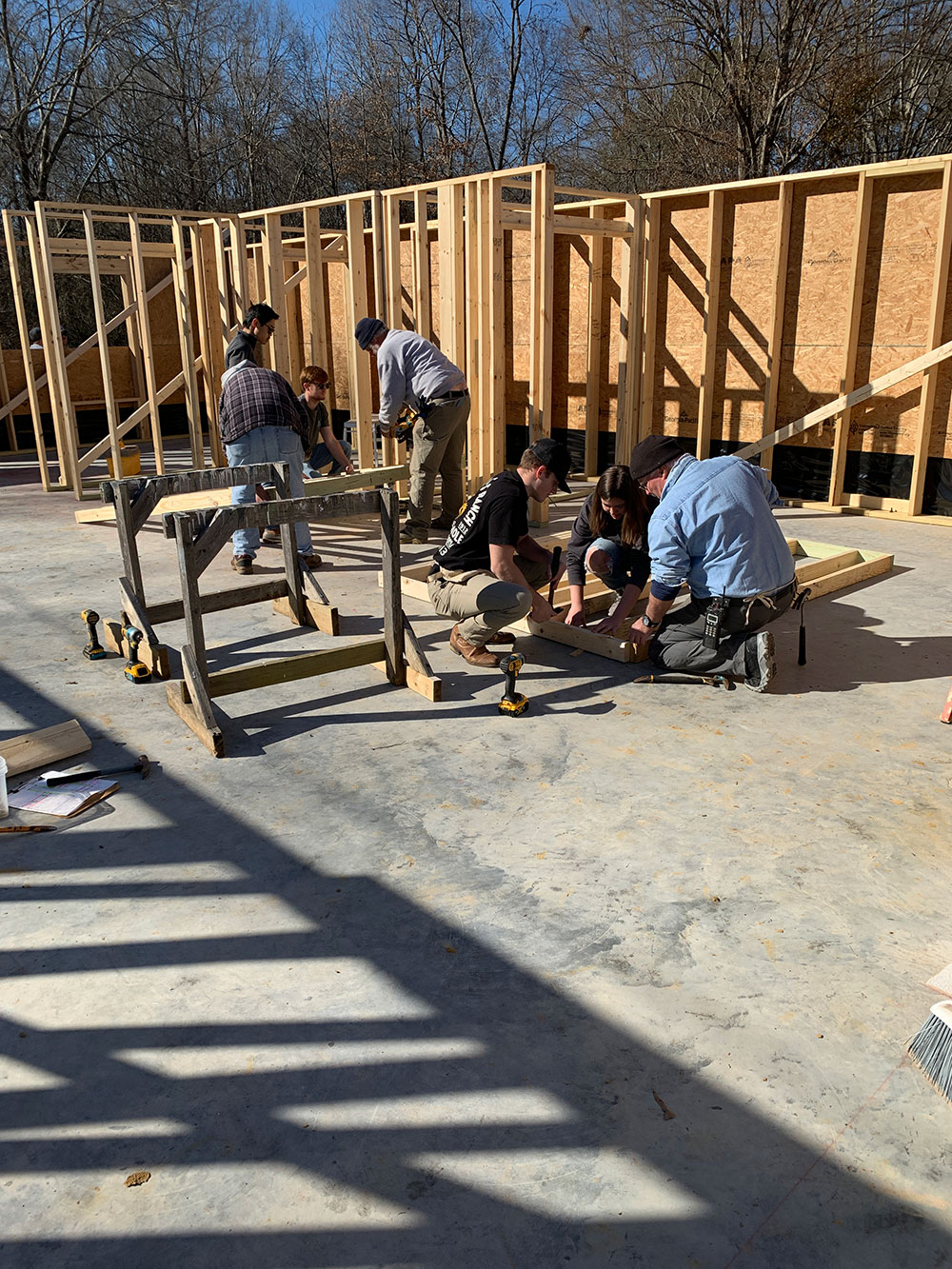 group working on two separate wood wall frames on concrete slab