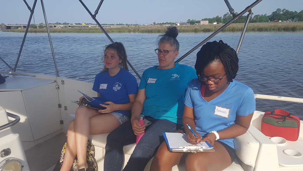 Internship boat trip and orientation. Elizabeth Englebretson (staff at GCCDS) sits in the middle of two of the student interns on a fishing boat