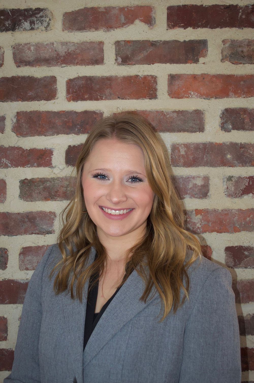 headshot of Kat Sykes in front of red brick