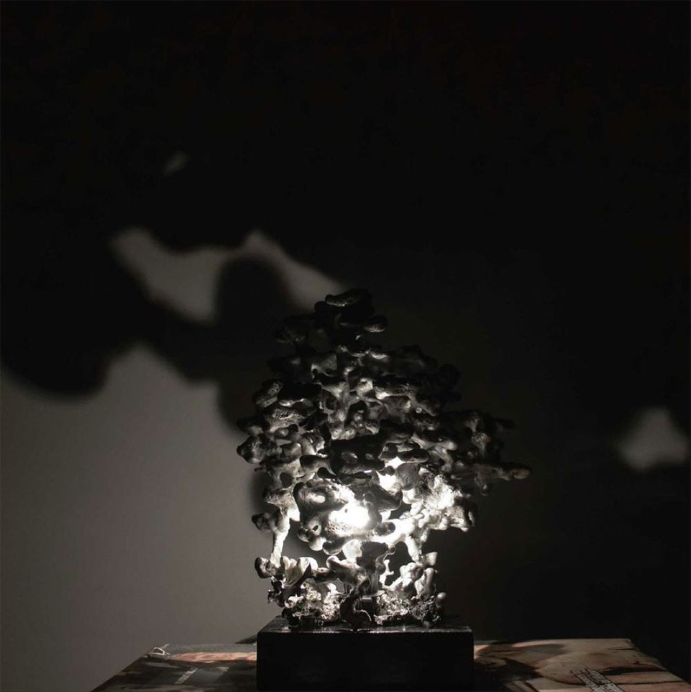 black and white photo of "Colonies" lamp by Mississippi State Interior Design student Marygrace Lee. Lamp is lit and was created the piece by pouring 100% recycled melted aluminum into an ant bed 