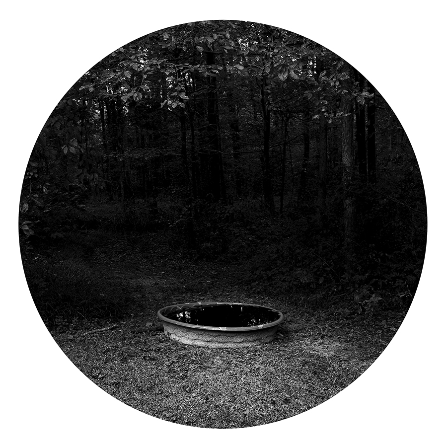 Black and white photograph of a plastic pool outside on the grass.