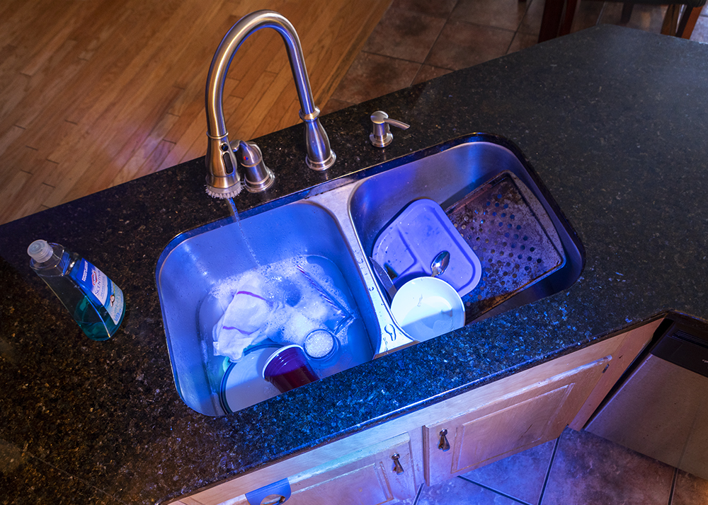 A photograph of kitchen sink with a blue light appearing from inside of it