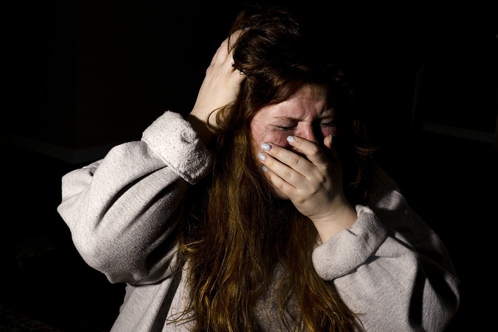 A photograph of a girl screaming with her hand over her mouth