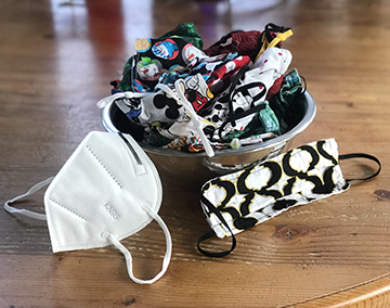 Color photograph of a glass bowl full of cloth facemasks.