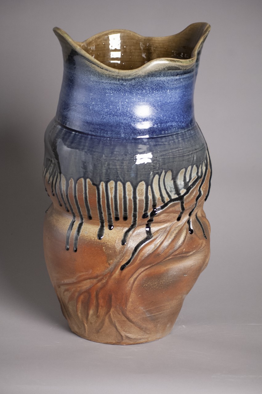 Vessel with blue drips and white spotting accents along the top. Crown shaped rim 