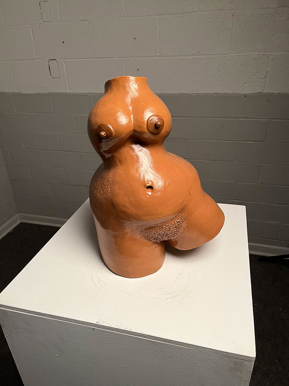 A small fleshy brown sculpture with nipple and belly rings