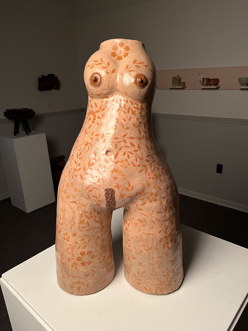 A tall fair skinned sculpture with brown floral tattoos covering the entire piece