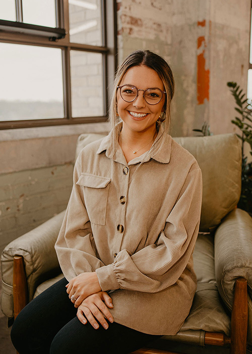 Megan Henry in tan sits on tan couch