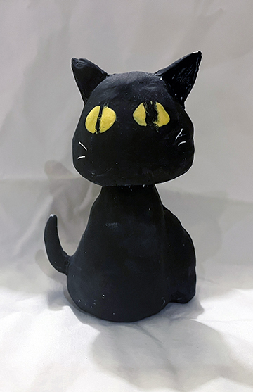Clay sculpture of a black cat sitting.