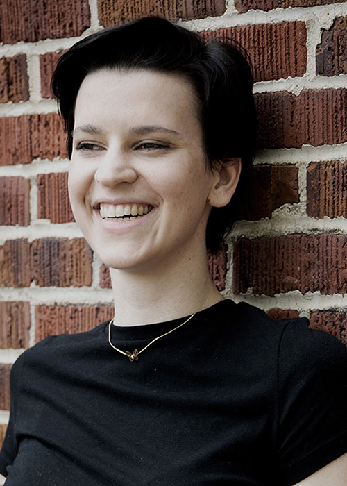 Natalie Allen headshot - black shirt, brick background