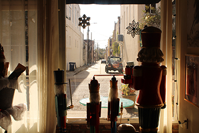 Color photograph of nutcrackers looking out a window at a street.