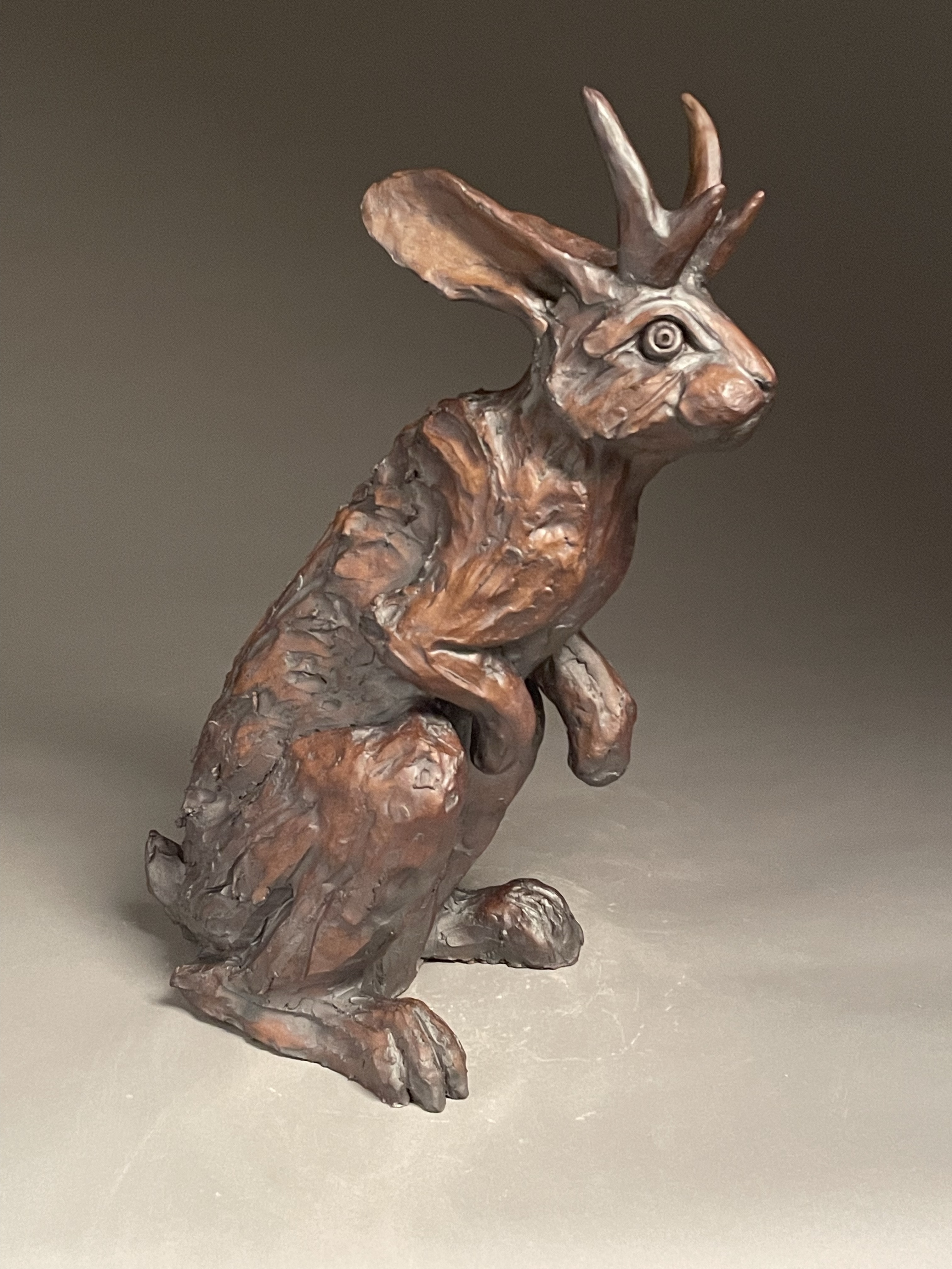 Ceramic jackalope sculpture standing on its back legs with a red oxide glaze
