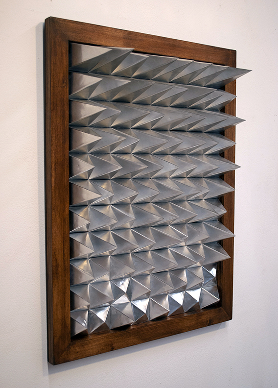 Wall sculpture with rows of metal spikes inside a wooden frame.