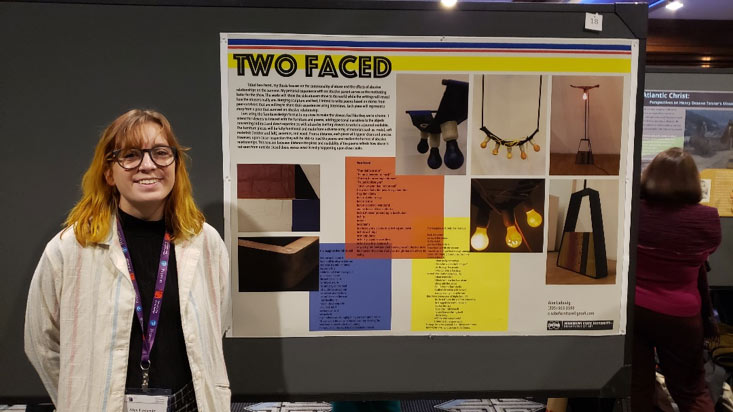 female student posing to the left of a display board